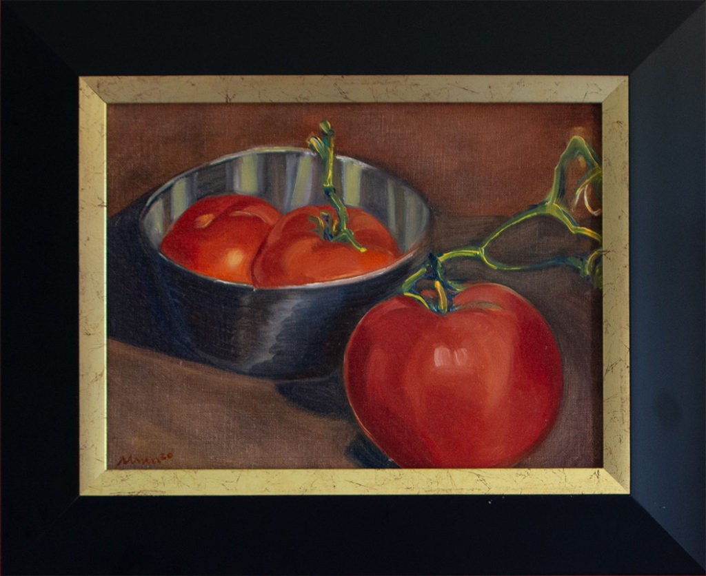 Three bright red tomatoes, two in a reflective stainless steel bowl